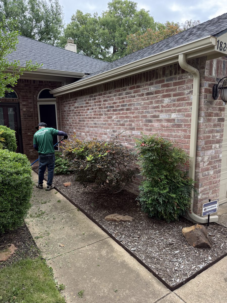 Backyard Boys crew member servicing the exterior of a brick home